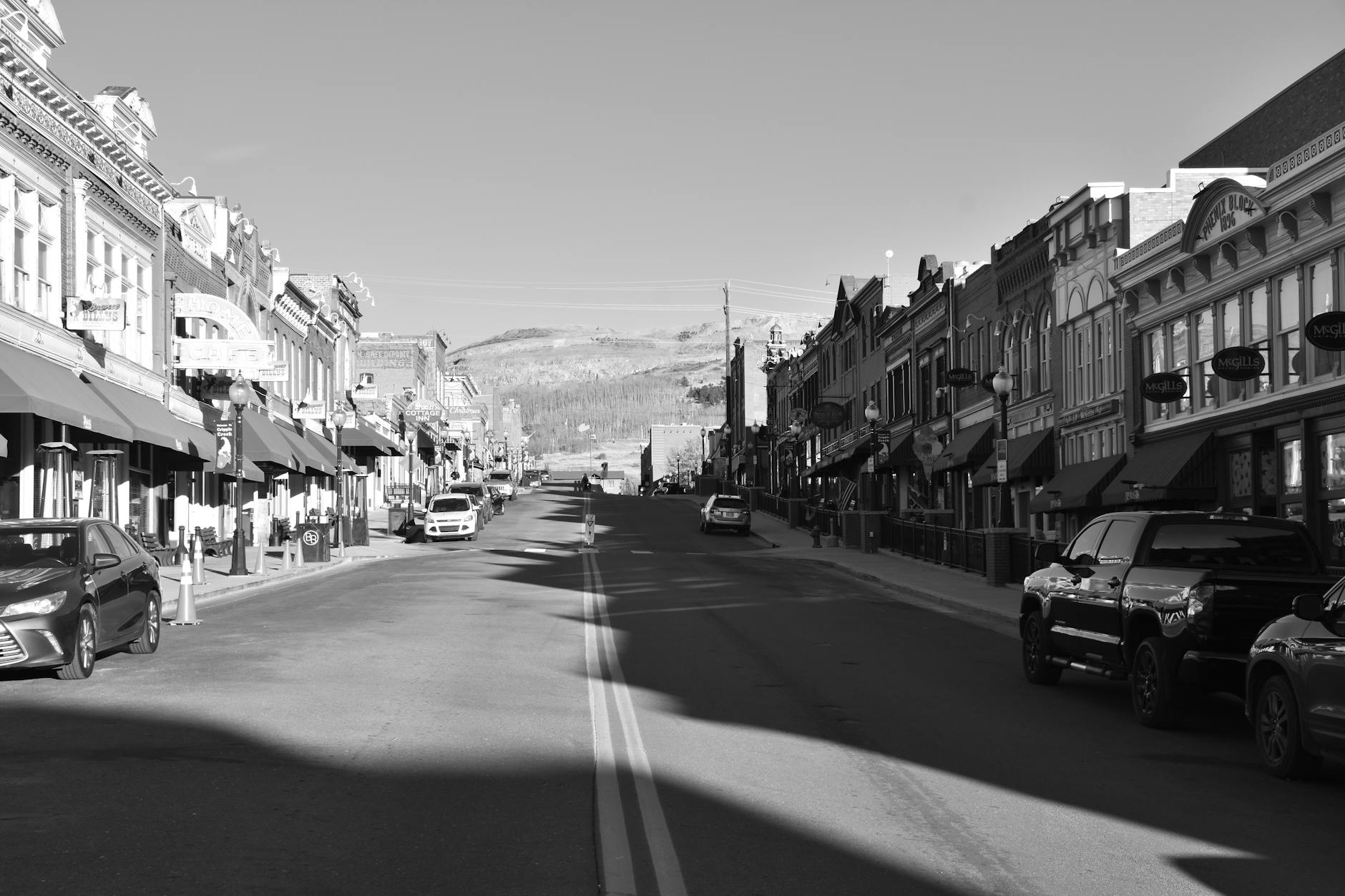 Czarno-biała ulica małego miasta z zabytkowymi budynkami i autami