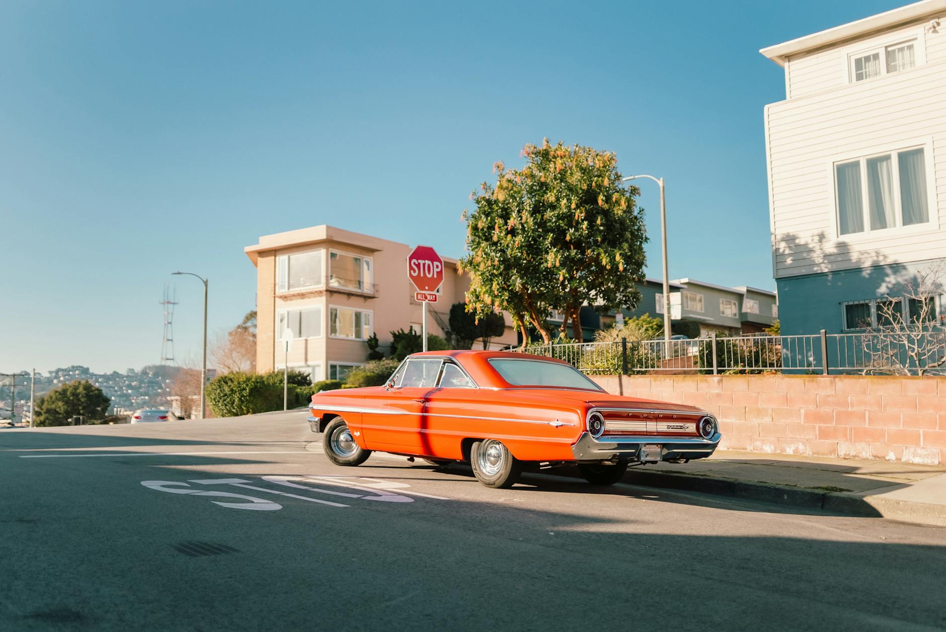 Czerwony zabytkowy samochód na słonecznym skrzyżowaniu obok znaku stop