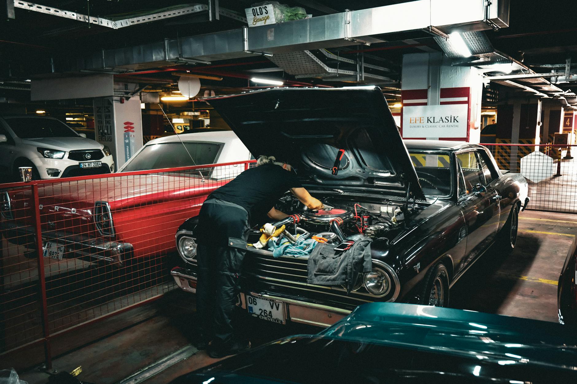 Mechanik naprawiający silnik klasycznego Forda w podziemnym garażu