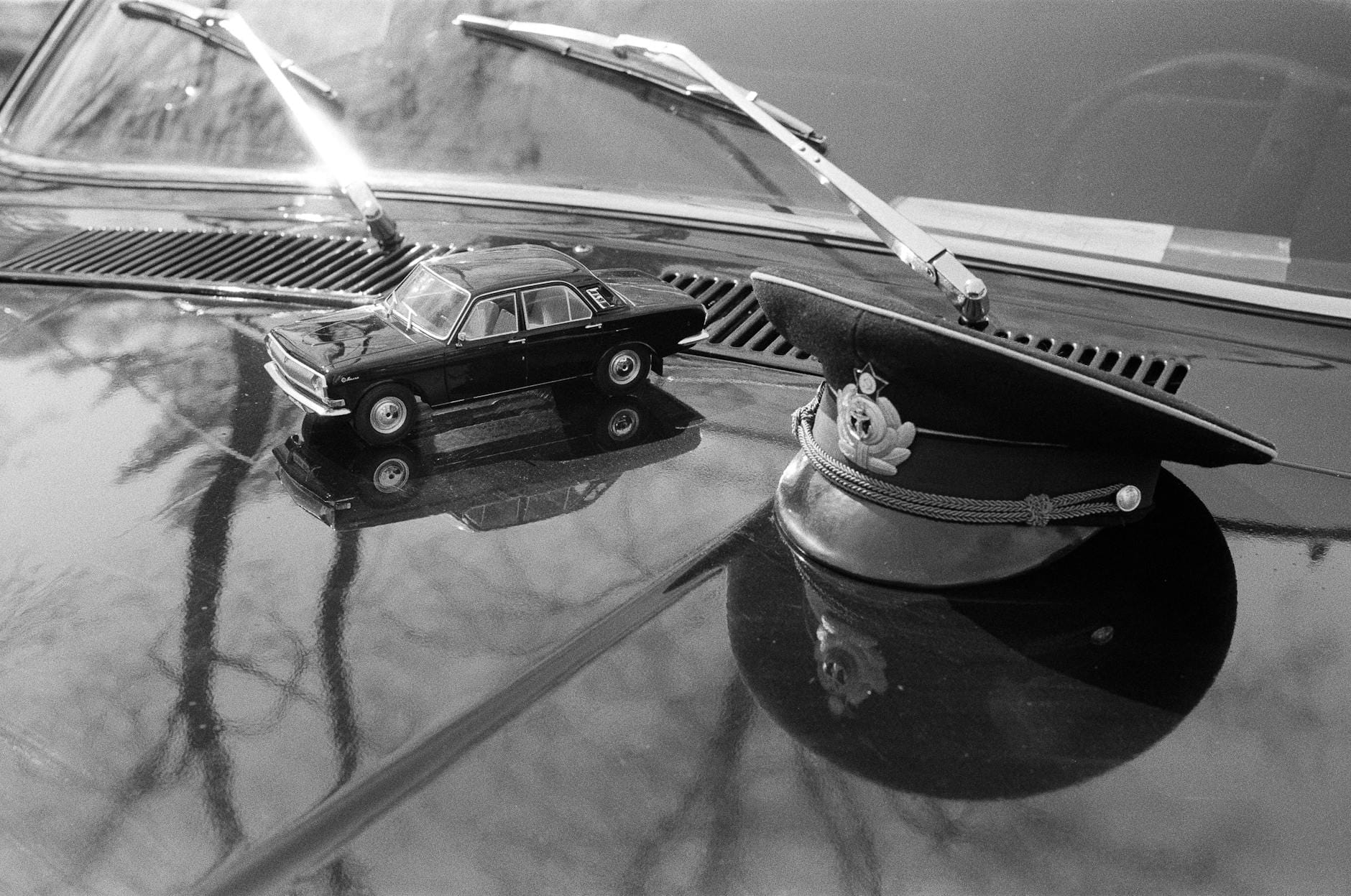 Miniaturowy radiowóz i czapka policyjna na masce zabytkowego auta