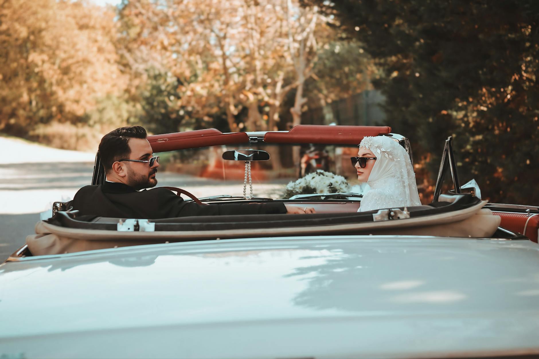 Para młoda w kabriolecie jedzie malowniczą trasą po ceremonii ślubnej