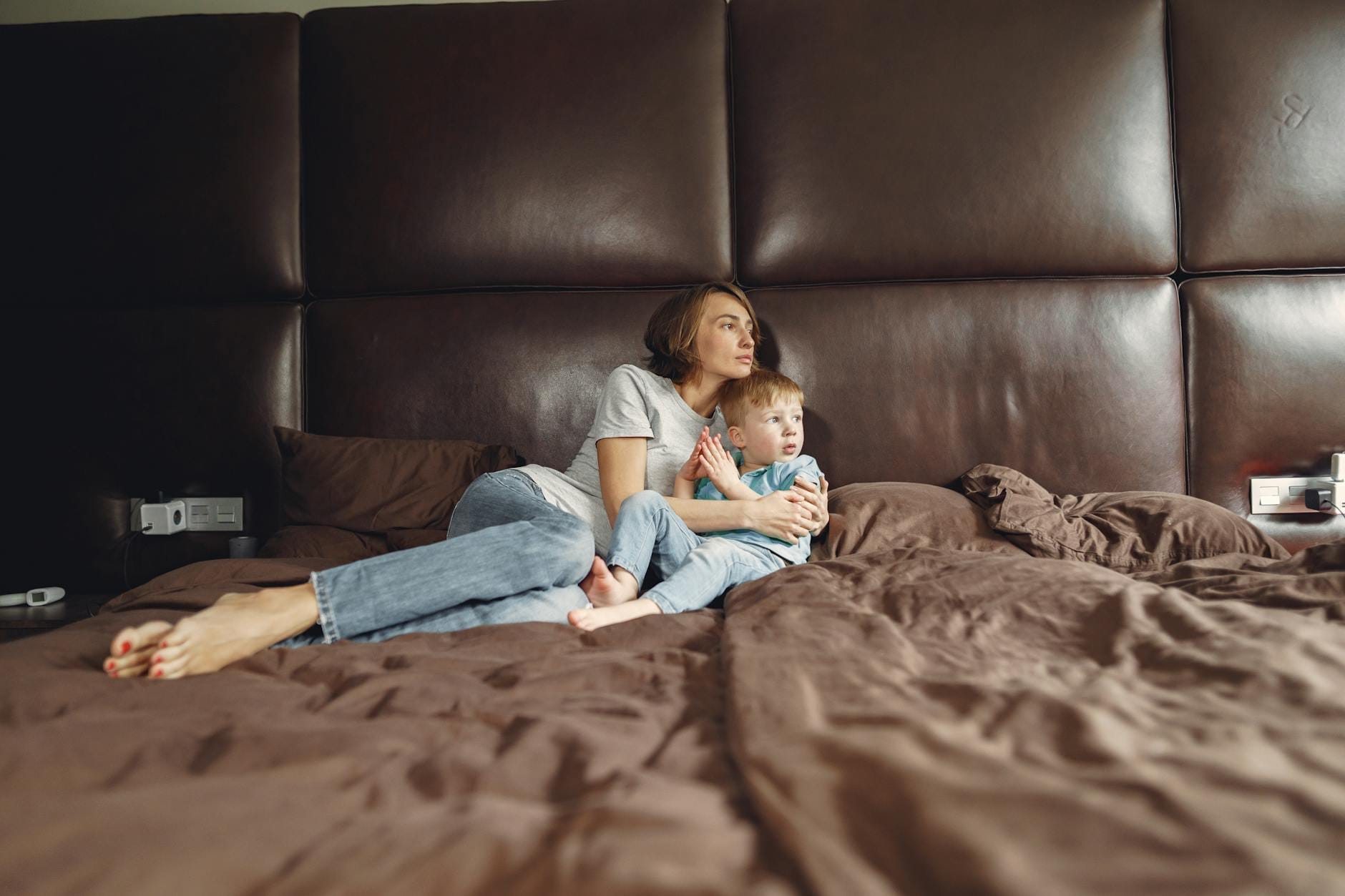 Mama przytula syna w przytulnej sypialni, daje mu poczucie bezpieczeństwa