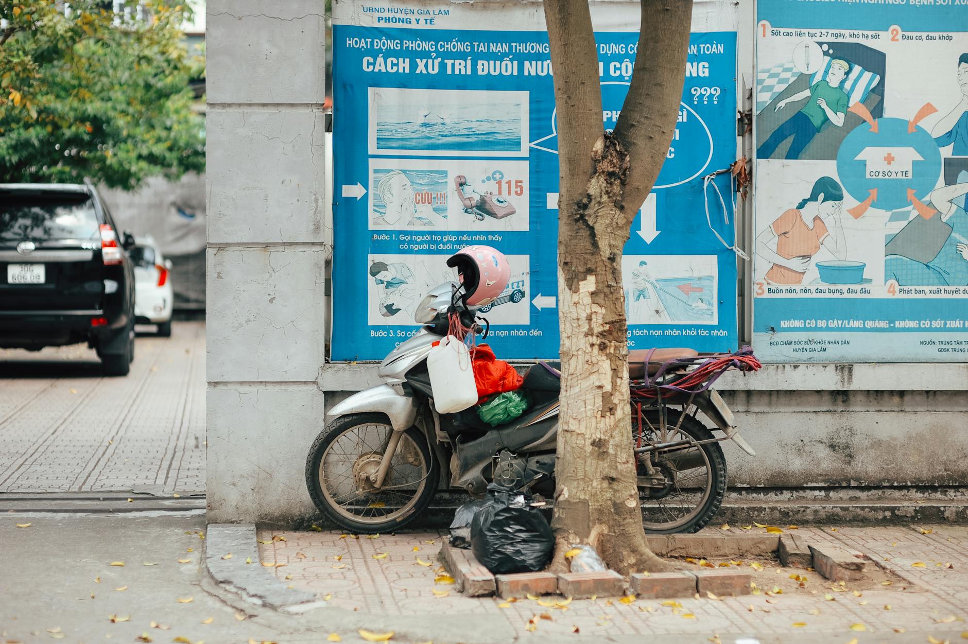 Motocykl z różowym kaskiem przy murze z plakatami informacyjnymi