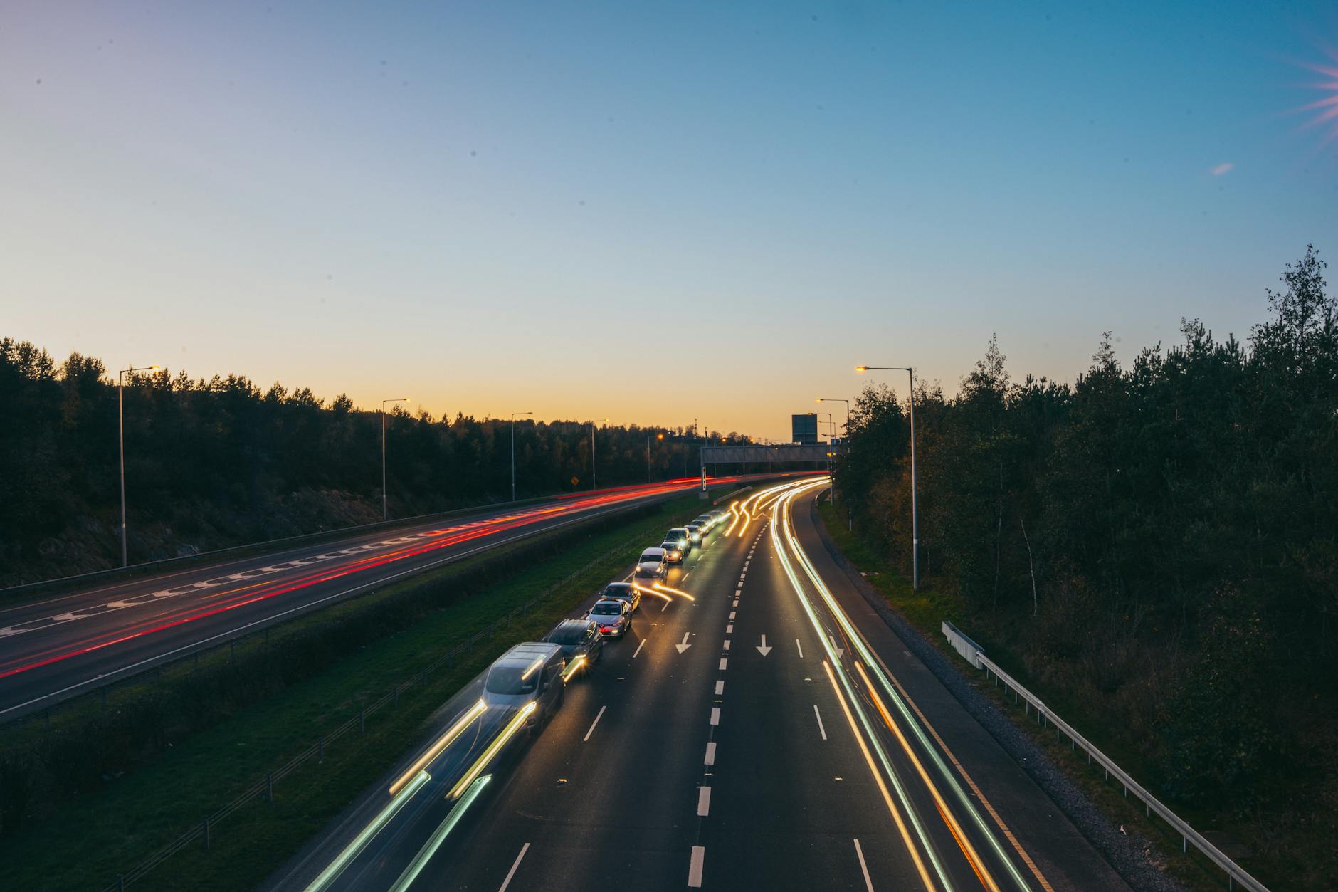 Światła samochodów na autostradzie podmiejskiej o zachodzie słońca