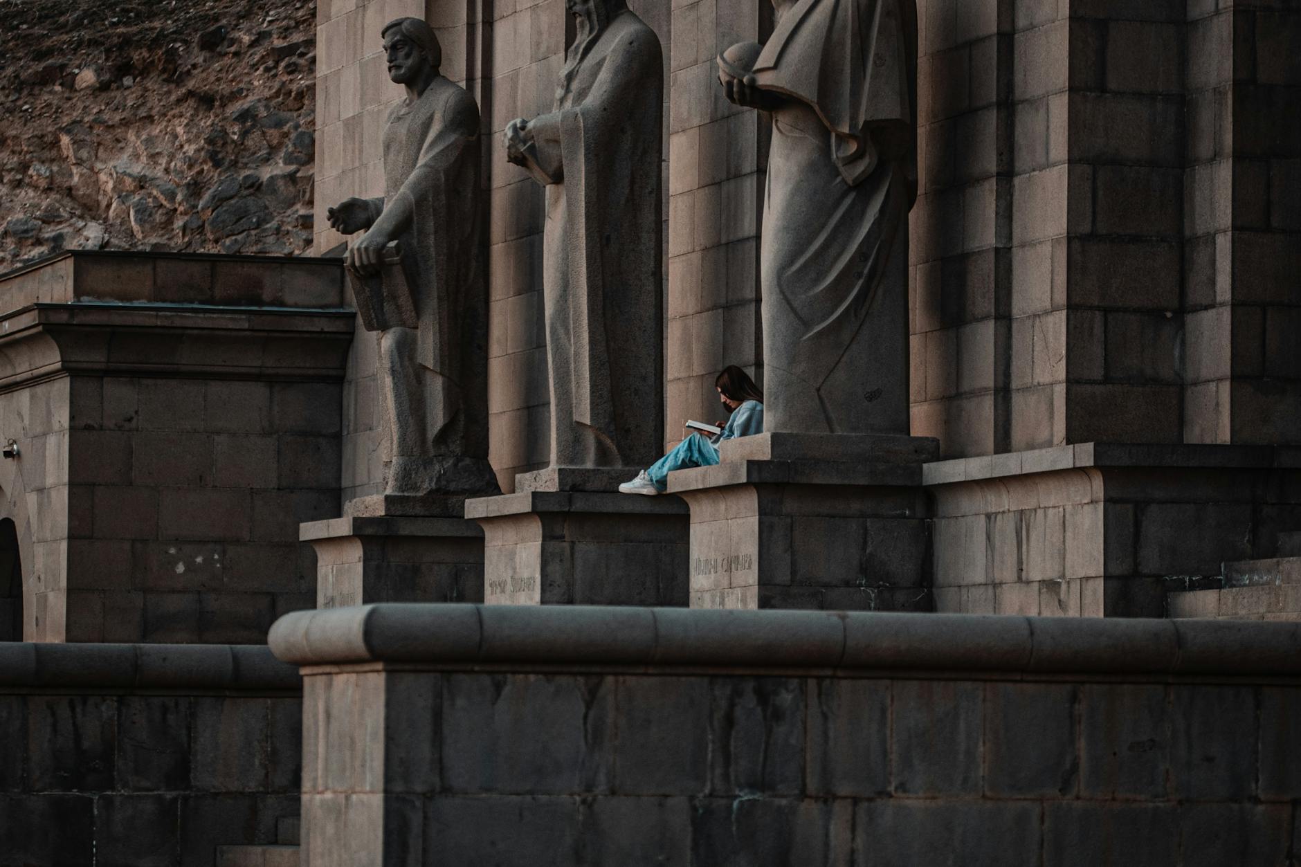 Osoba czyta książkę wśród starożytnych kamiennych posągów