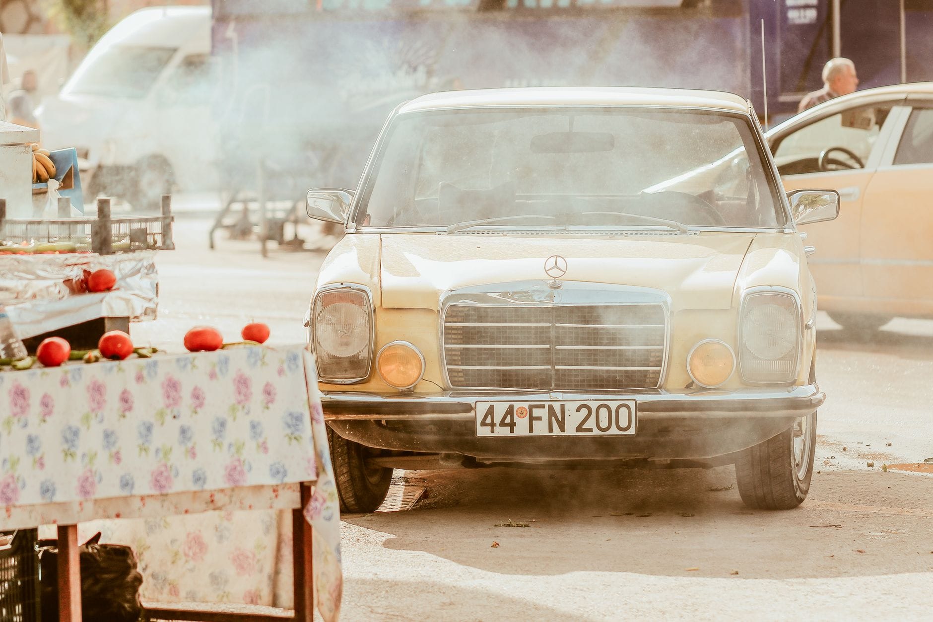Zabytkowy mercedes na gwarnym targu ulicznym w kolorowym dymie