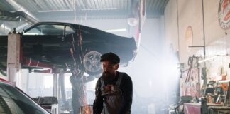 Mechanik naprawiający samochód w warsztacie z lecącymi iskrami